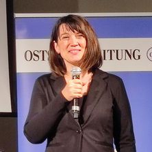 Justizministerin des Landes Mecklenburg-Vorpommern, Frau Jacqueline Bernhardt, mit Mikrofon in der Hand beim Grußwort der Veranstaltung